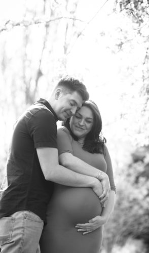 Happy couple cuddling for maternity portraits in Cumbria