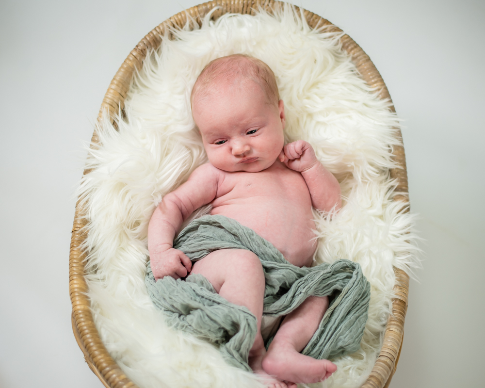 Baby lying in basket, newborn photographers