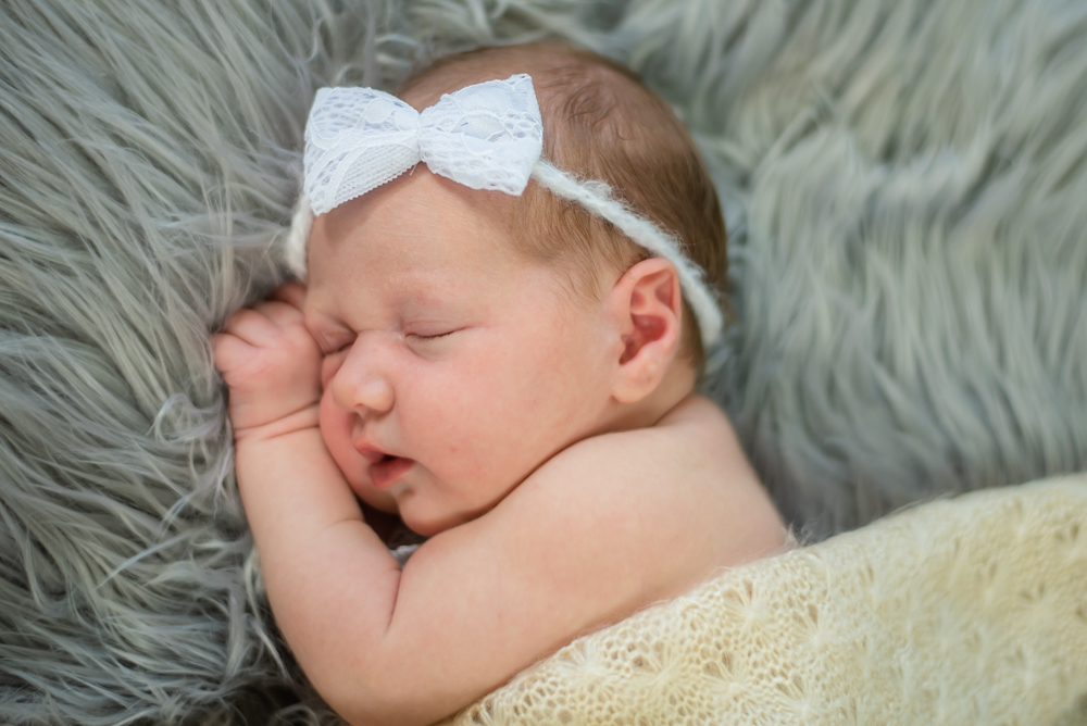 baby girl wearing bow under blanket, whitehaven newborn photographers