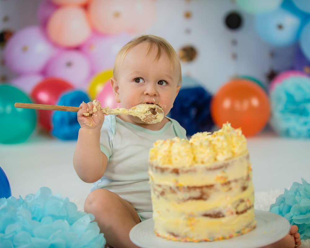Freddie smashing his cake with a spoon, cake smash cumbria baby photographers