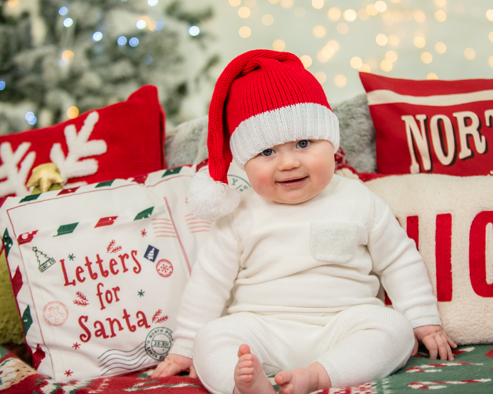 Boy sitting on Christmas rug in Santa hat, Christmas mini sessions, Wigton baby photographers